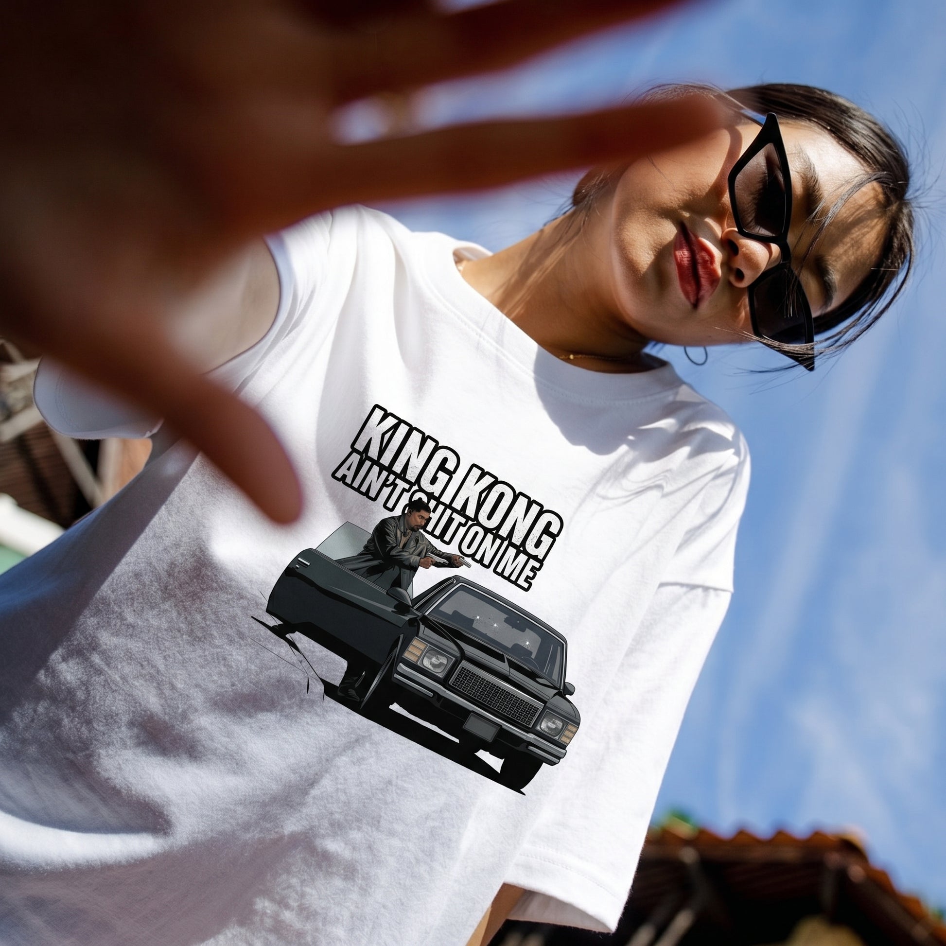 Person wearing a white t-shirt with a graphic and text, standing outdoors.