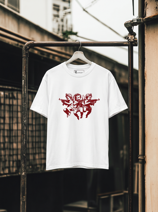 A white short-sleeve t-shirt hanging on a metal rack outdoors, featuring a red graphic print of three cherubs holding guns across the chest.