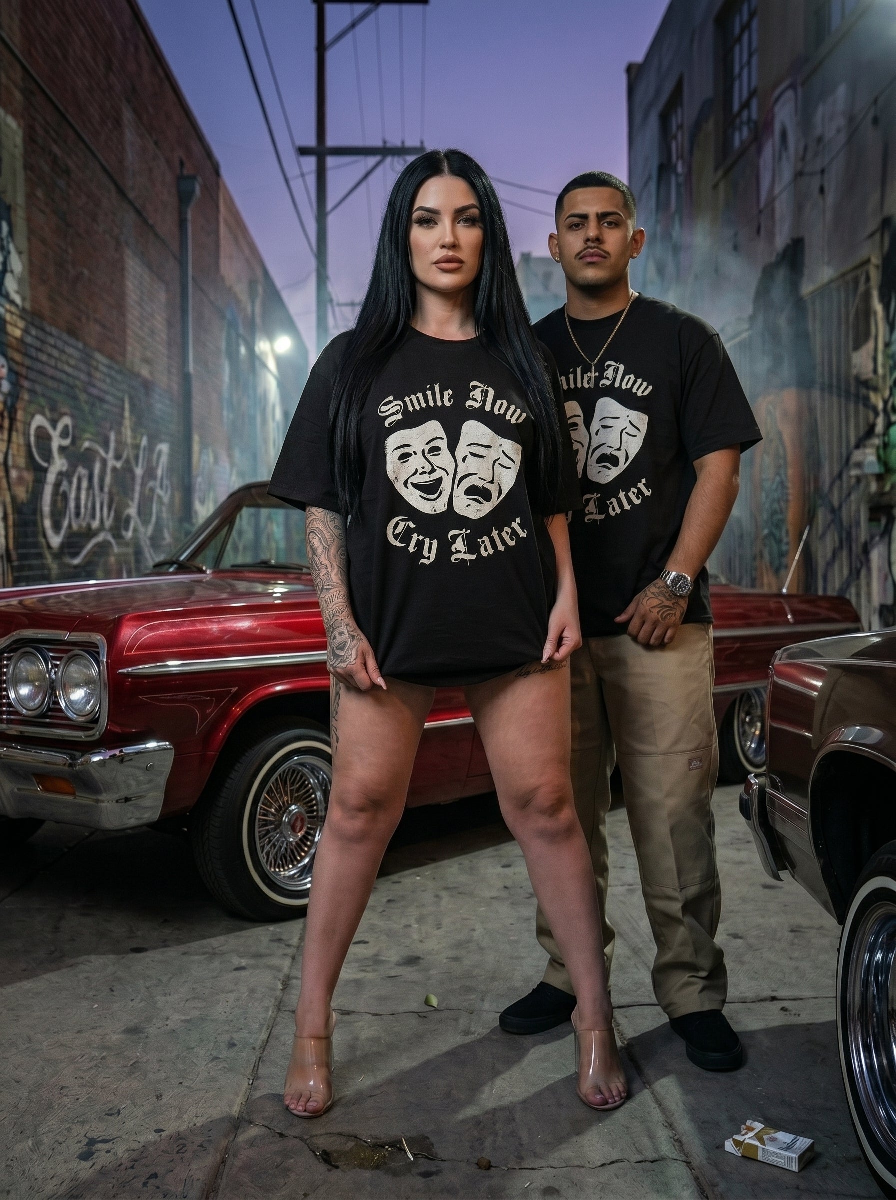 Two people wearing black t-shirts with a graphic design in an urban setting.