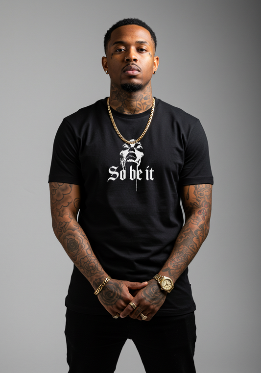 Man wearing a black t-shirt with white text "So Be It" on a gray background streetwear style by LowriderTV