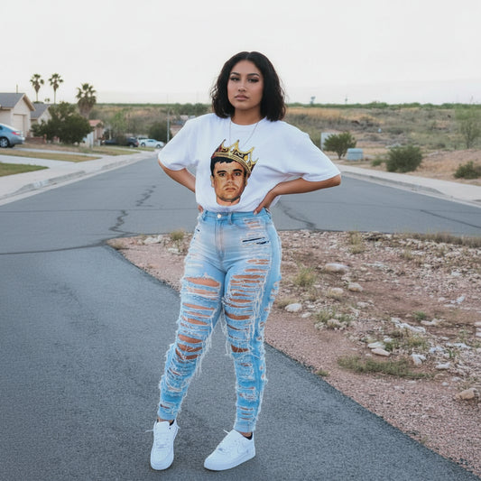 Person wearing a white t-shirt with a graphic design and ripped jeans standing on a suburban street.